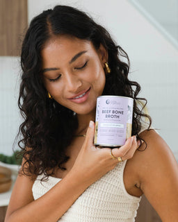 A woman with dark hair holds a tin of beef bone broth adaptogenic mushroom