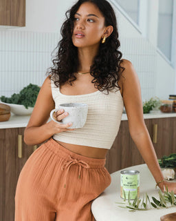 A woman with dark hair holds a tin of beef bone broth garden herb